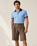 AI-generated styling visualization: male model wearing Luvere Capri Tailored Shorts in Espresso with the Sky Riviera Polo and espresso collar and cuffs, based on original garment photographs.